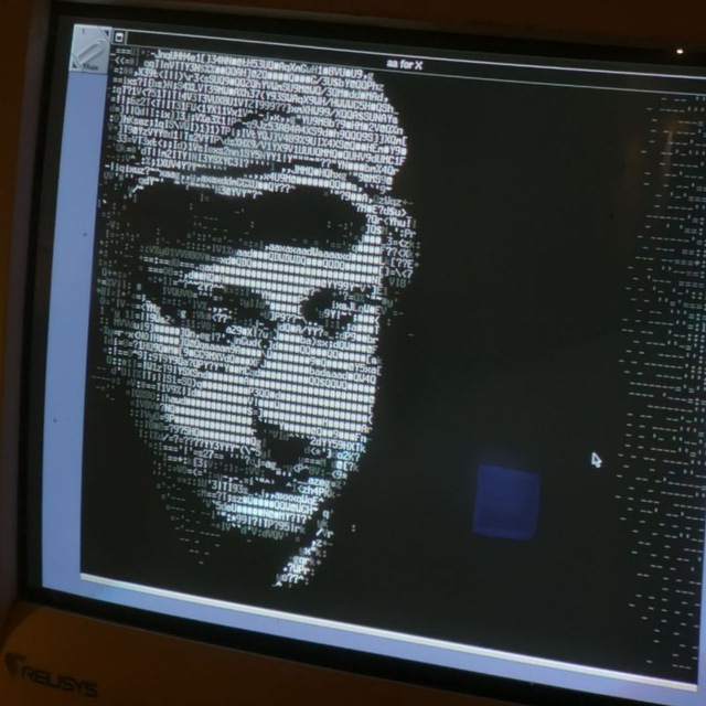 Enrico Bisenzi alias Ferry Byte ritratto in stile ascii art con cappello baffi e occhiali che osserva una serie di codice che si sta generando davanti ai suoi occhi